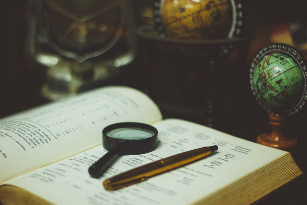 book, pen and magnifying glass